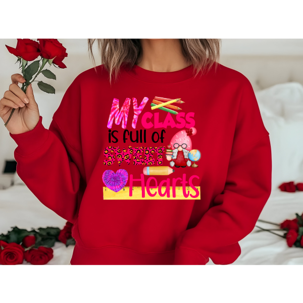 A person holding a bunch of red roses and wearing a red sweatshirt with the text 'MY CLASS IS FULL OF SWEETHEARTS' and various heart-related graphics.