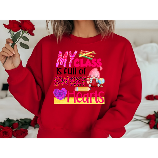 A person holding a bunch of red roses and wearing a red sweatshirt with the text 'MY CLASS IS FULL OF SWEETHEARTS' and various heart-related graphics.