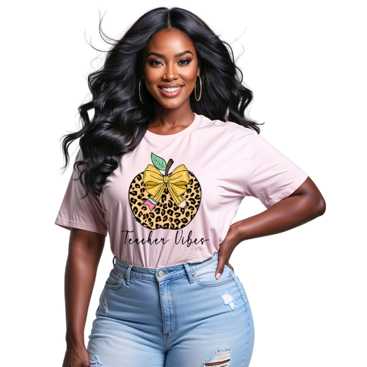 Woman wearing a pink t-shirt with a leopard print apple design and 'Teacher Vibes' text.